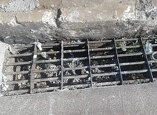 Empreiteira lacra boca-de-lobo de concreto com restos de material de recapeamento