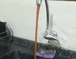Moradora mostra a cor da água em residência de Dourados